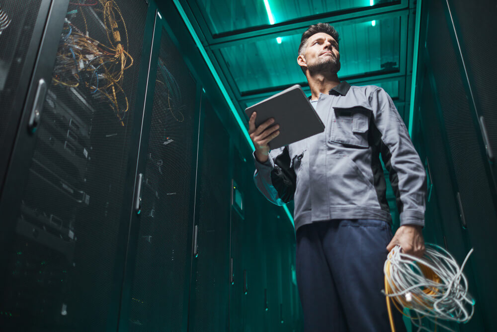 low angle portrait mature network engineer using digital tablet server room during maintenance work data center copy space